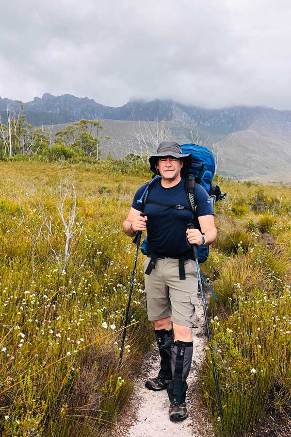 Darren-yellow-buttongrass-plains Image of darren crossing vibrant yellow buttongrass plains.