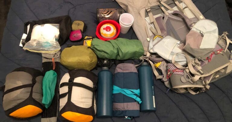 A group of camping equipment on a bed